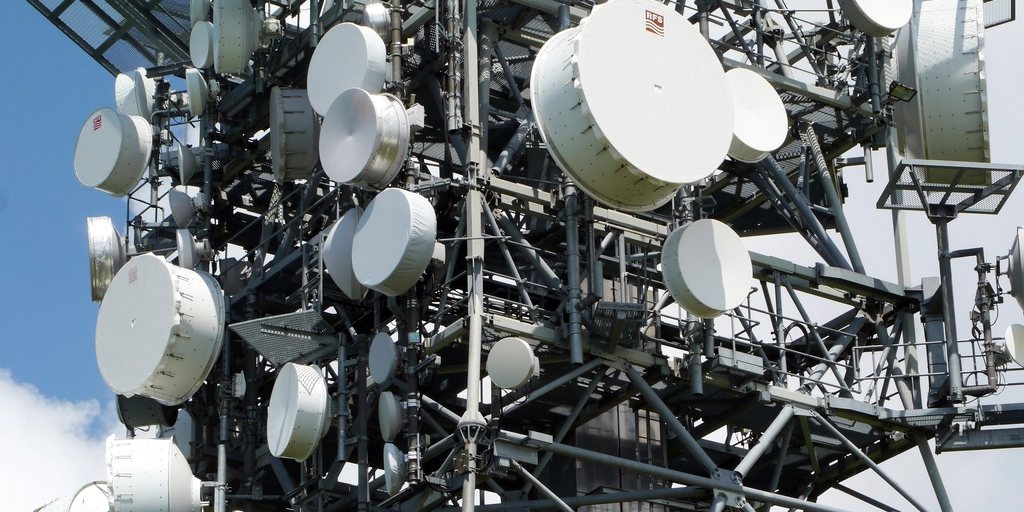 Torre de telecomunicações coberta de antenas parabólicas e de micro-ondas.