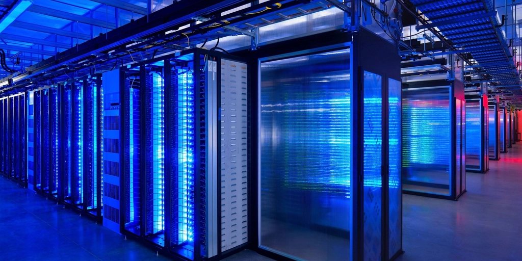 Corredor de um data center com racks de servidores iluminados em azul.