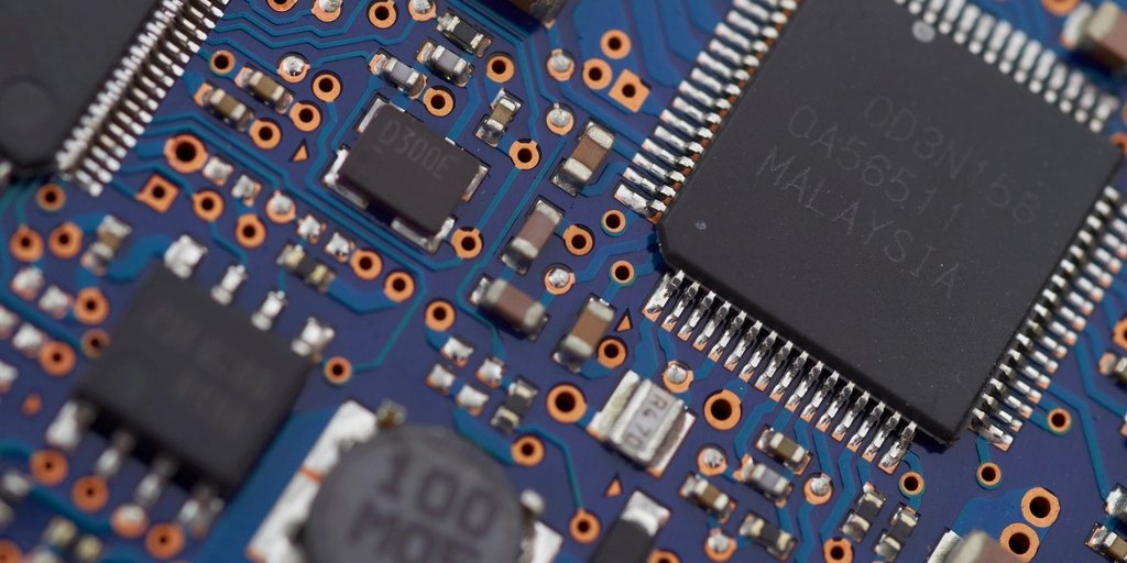 Detalhe de uma placa de circuito com chips e componentes eletrônicos.