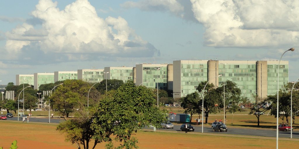 Prédios dos ministérios na Esplanada dos Ministérios, em Brasília, sob céu com nuvens.