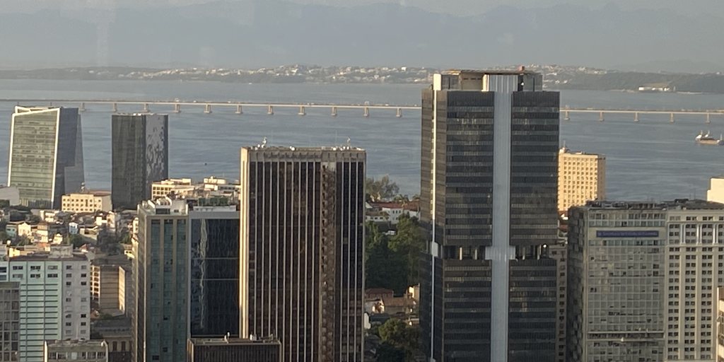 Vista aérea do centro do Rio de Janeiro com o edifício do Banco Central do Brasil e a Baía de Guanabara ao fundo.