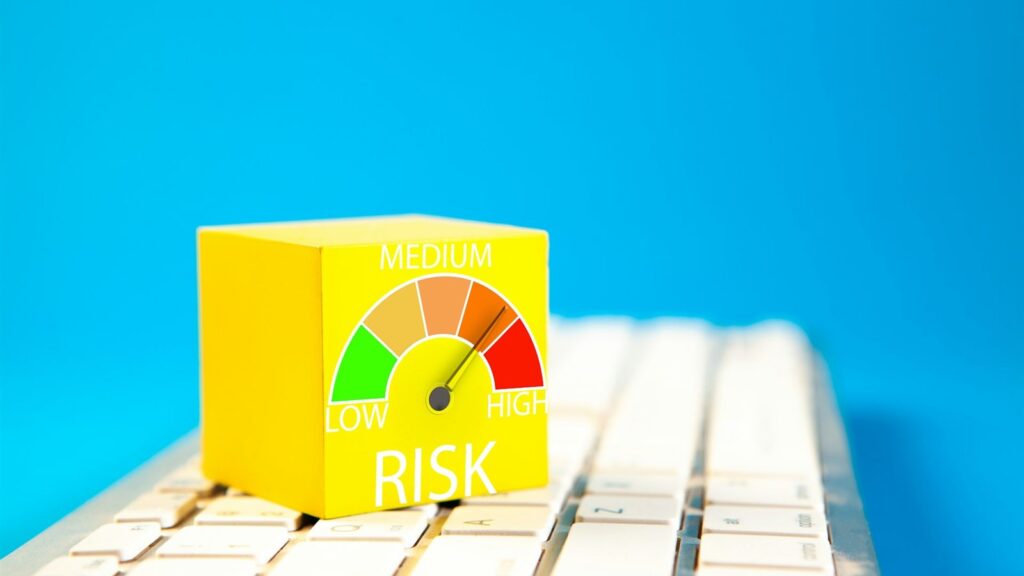 Cubo amarillo con un medidor de riesgo bajo, medio y alto apoyado sobre un teclado